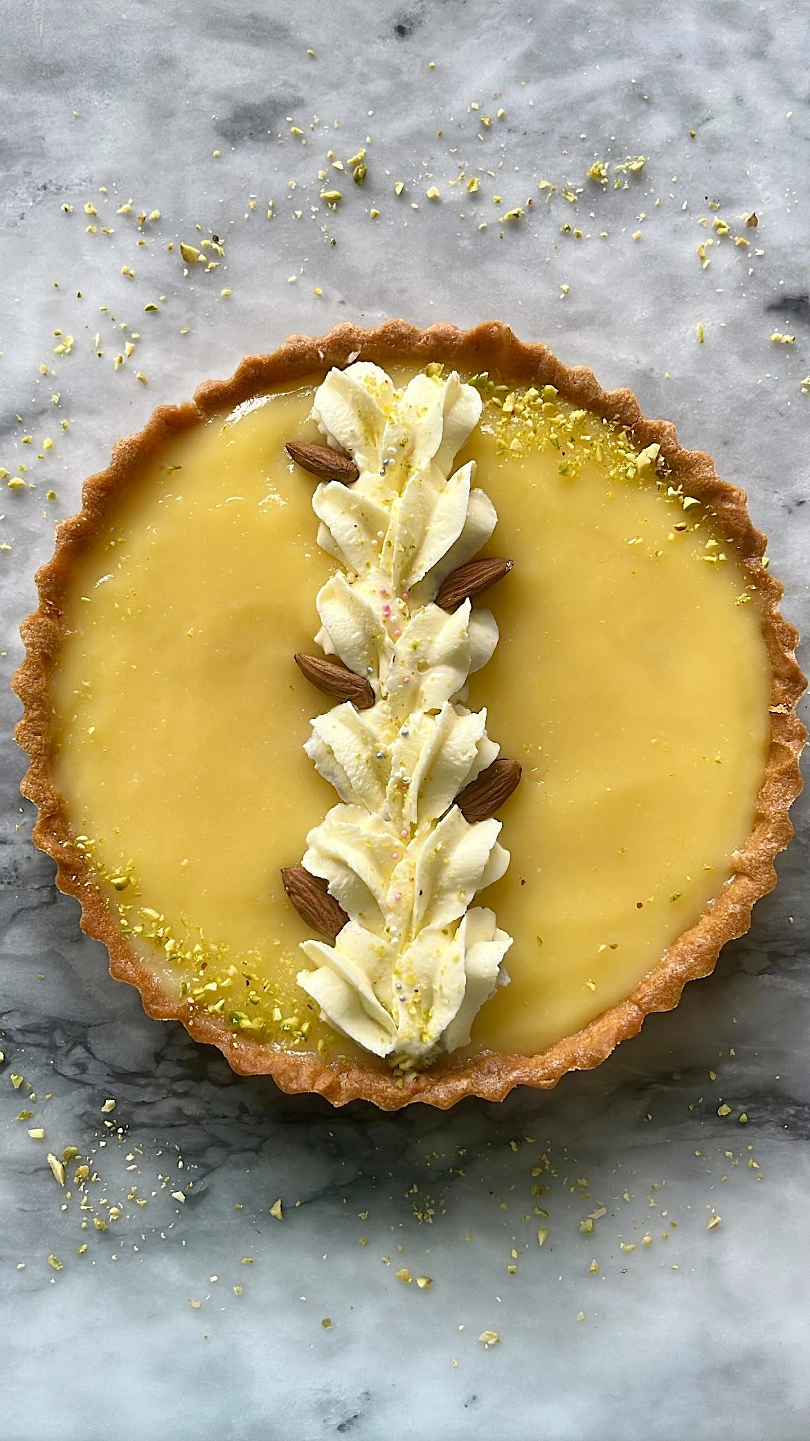 A lemon tart decorated with heart-shaped cream and almond on top